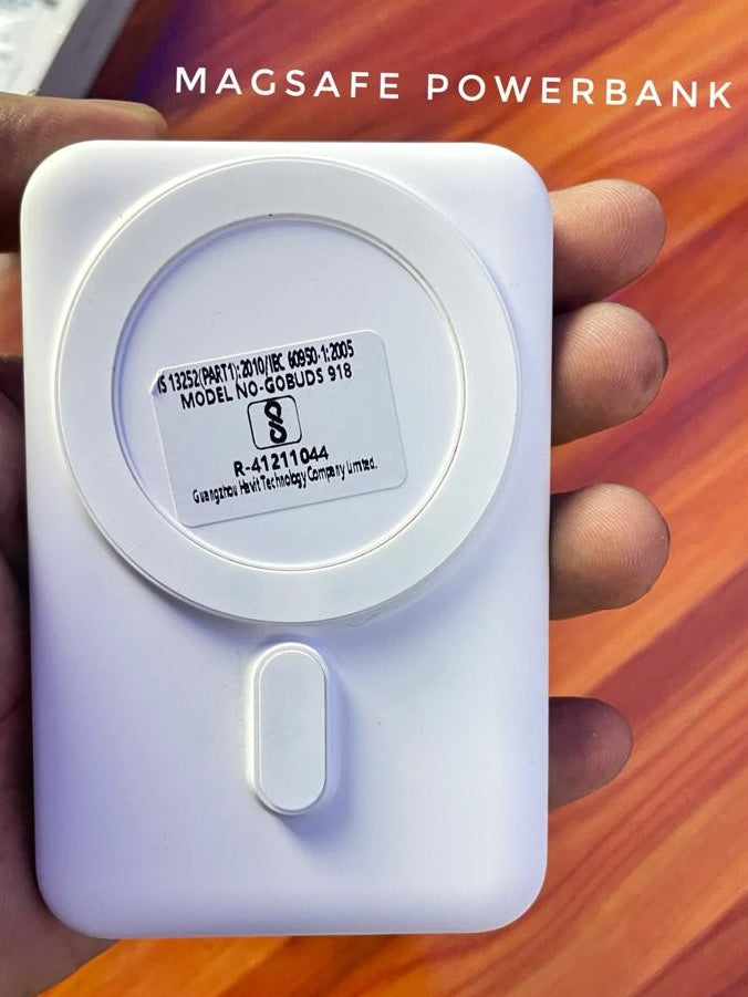 Magsafe power bank held in a hand with a wooden surface background